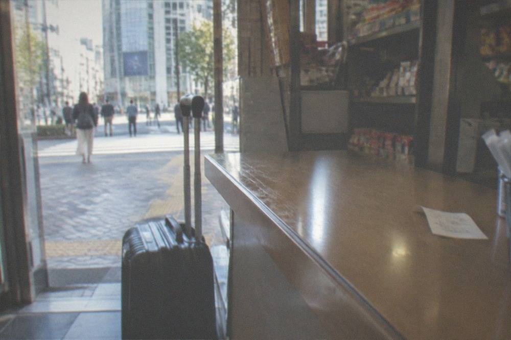 A shop counter with a suitcase parked beside it in a small Tokyo store