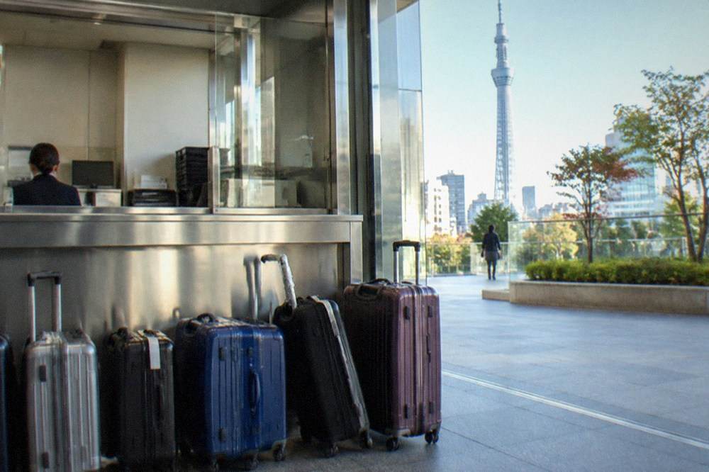 An attended station baggage counter with tagged suitcases lined up behind a service window