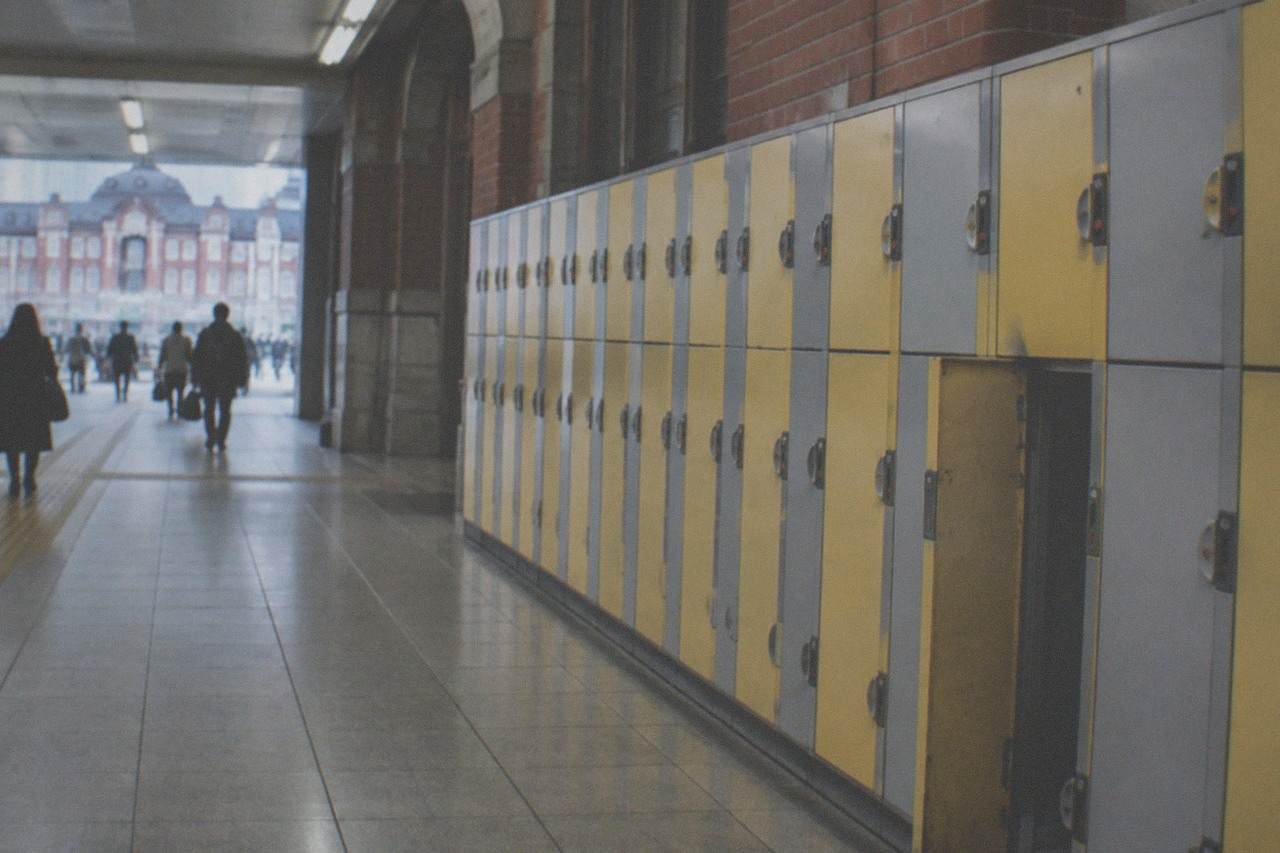 Rows of yellow and grey coin lockers along a Tokyo station corridor