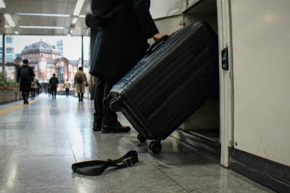 A suitcase being lifted into a large coin locker in a Tokyo station