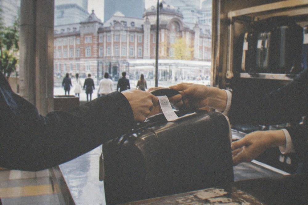 A staffed luggage storage counter with a suitcase being handed over across the counter