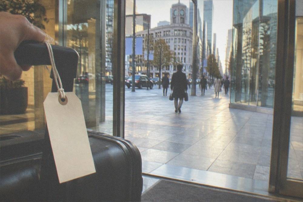 A numbered luggage claim tag tied to a suitcase handle in a hotel lobby