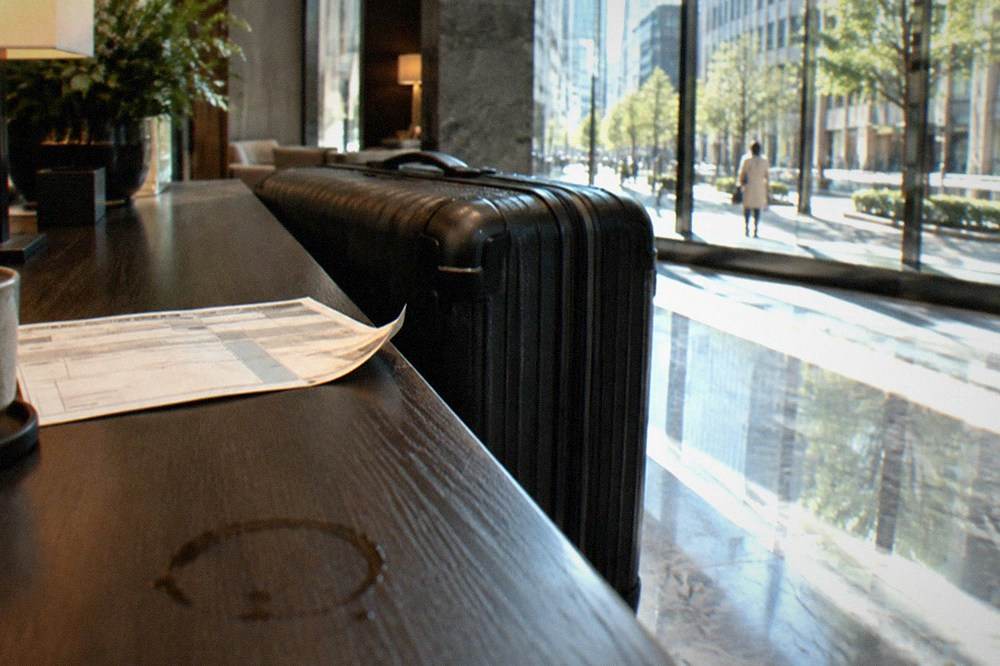 A large suitcase and a courier shipping label at a hotel front desk counter