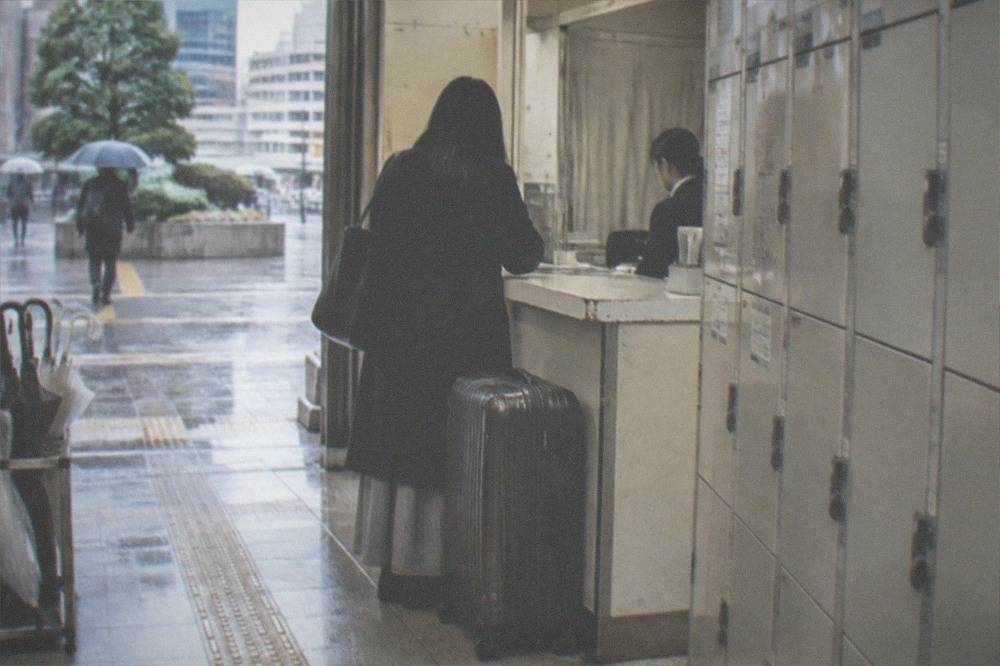 A shop counter with a large suitcase checked in beside a row of storage lockers