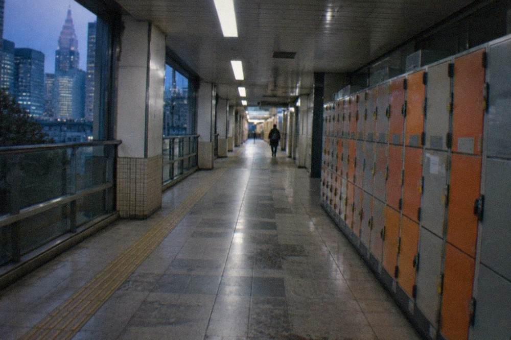Orange and grey coin lockers of different sizes along a Tokyo subway station corridor