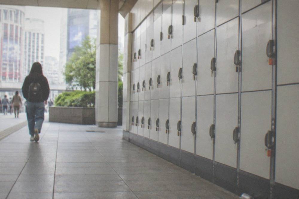 A traveller walking with a small backpack past a Tokyo station locker wall