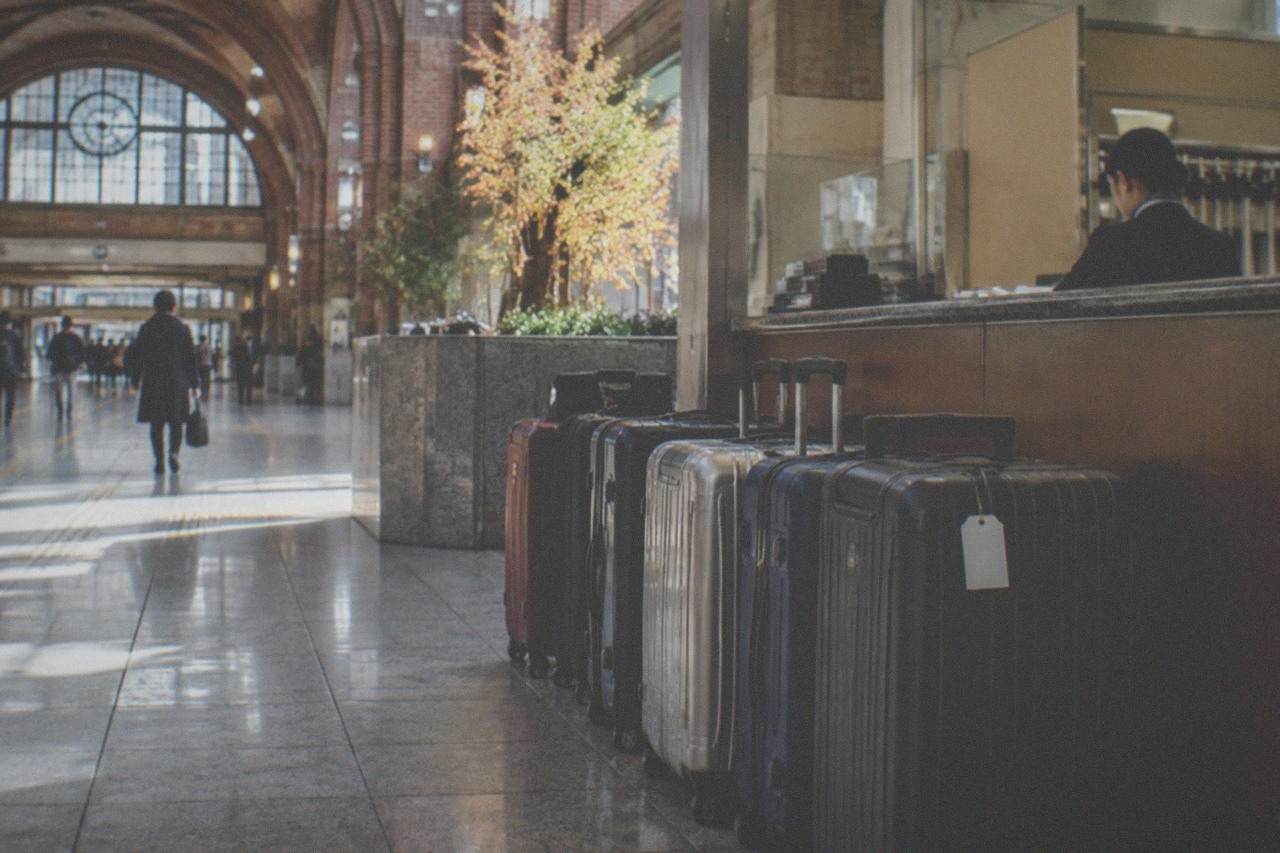 A row of large suitcases parked at a staffed luggage storage counter in a Tokyo station