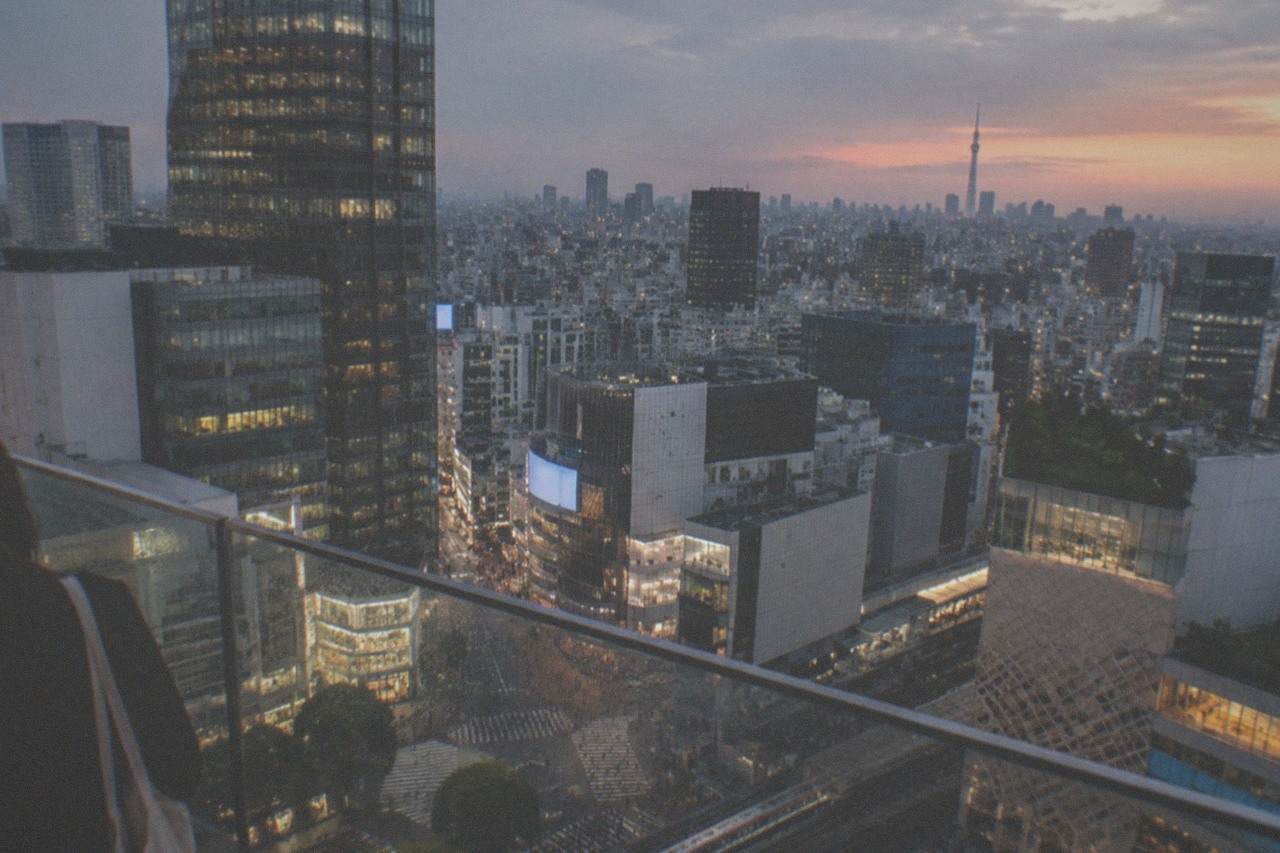 Open-air observation deck railing overlooking the Shibuya crossing and the Tokyo skyline at dusk