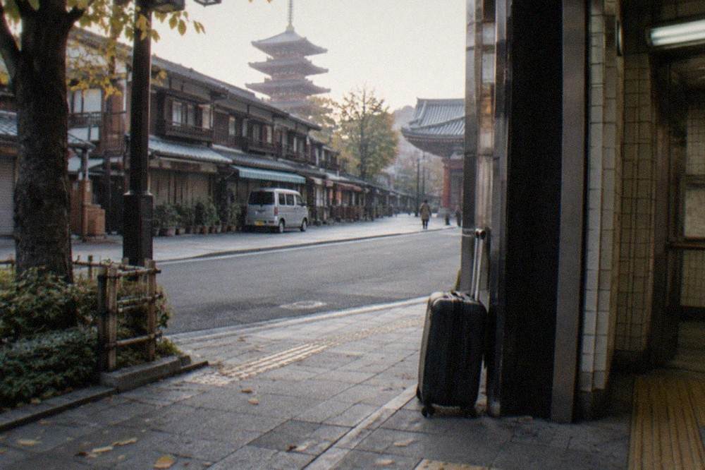 A suitcase standing beside a station entrance on a quiet Tokyo street