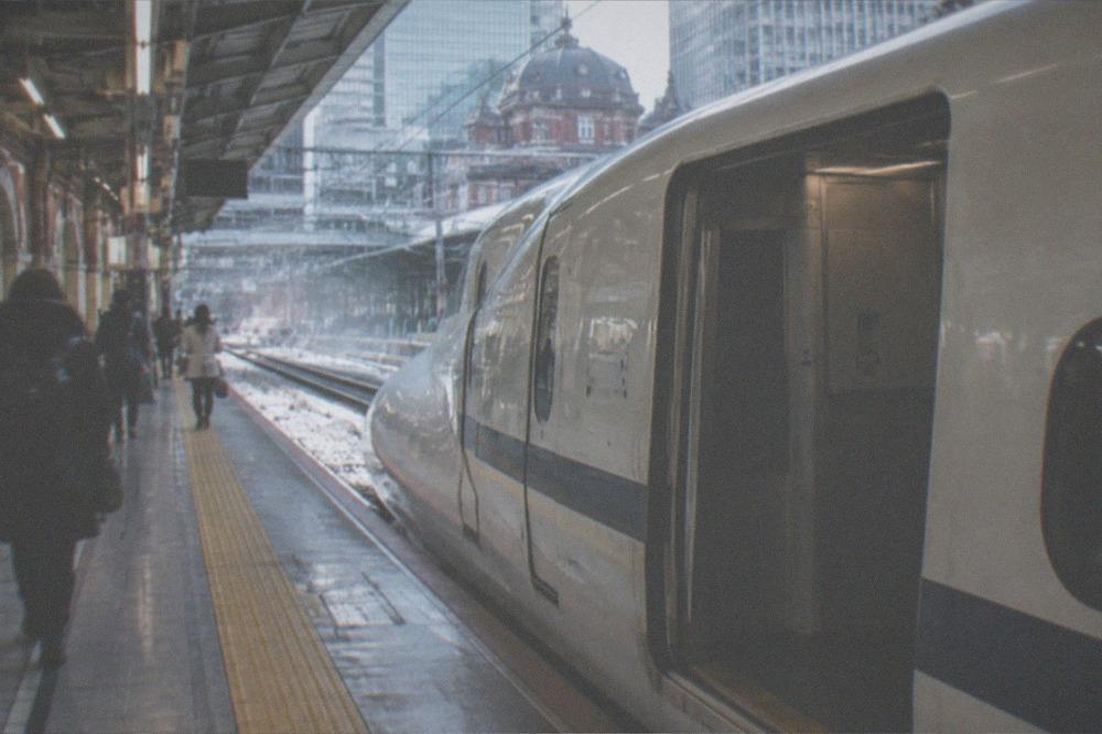 A bullet train waiting on a platform with an empty space for large luggage near the door