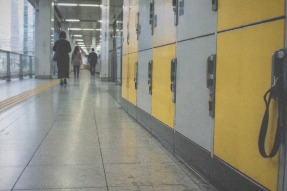 Rows of grey and yellow coin lockers along a subway corridor in Tokyo.