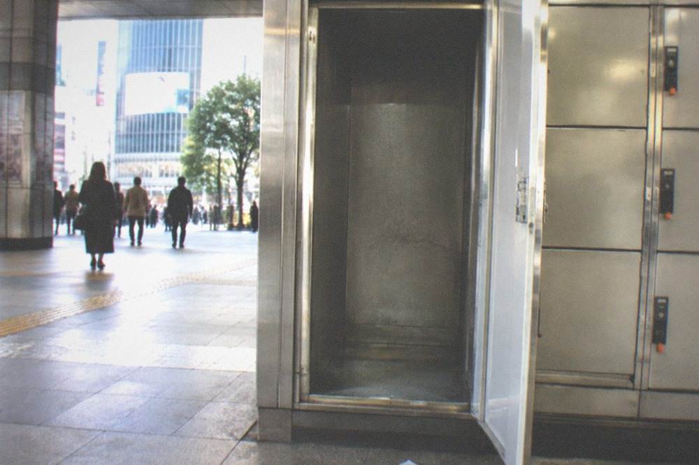 A large open coin locker beside a smaller tier of lockers in a Tokyo station.