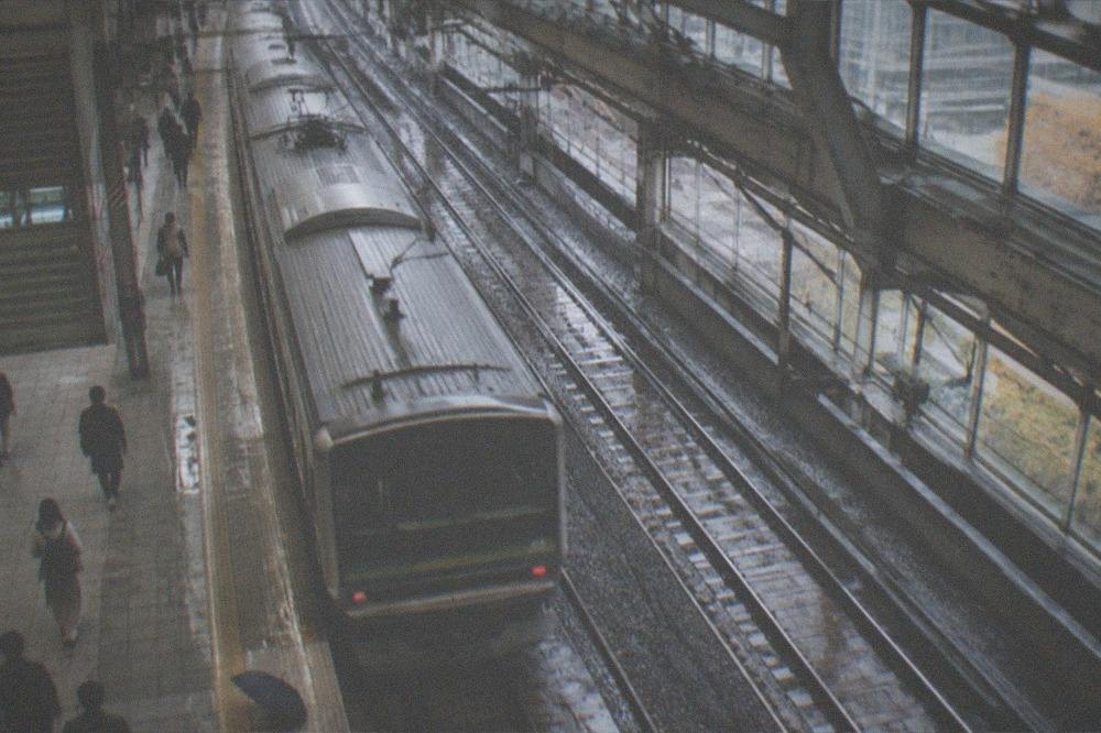 An overhead view of a Tokyo Station platform with a train pulling away beneath the canopy.