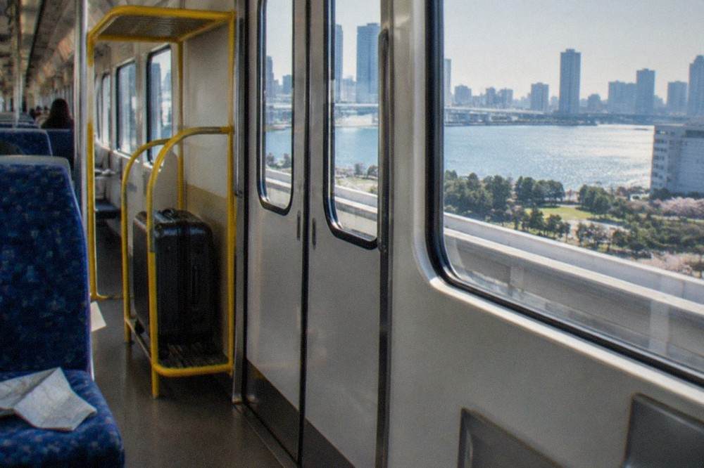 Interior of a Tokyo Monorail train with a yellow luggage rack beside the doors