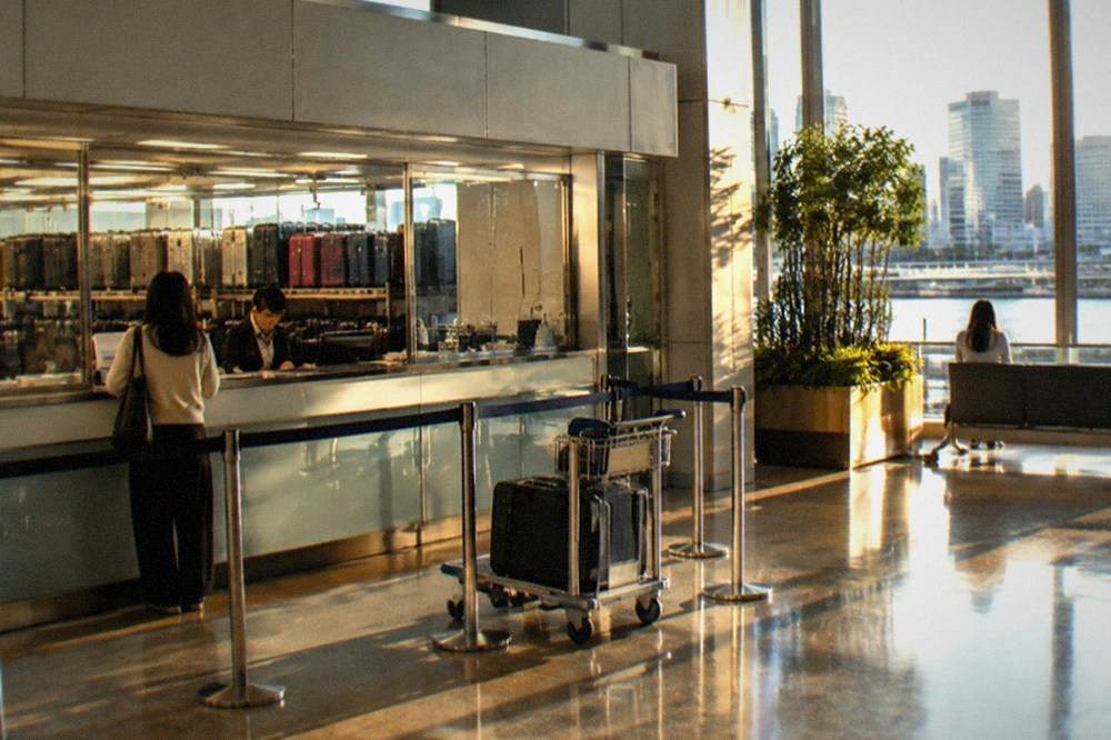 Arrivals lobby counter at Haneda Airport with staffed baggage storage sign