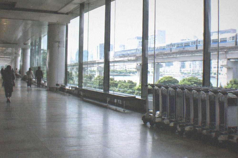 Wide airport corridor with trolleys and a monorail sign overhead at Haneda