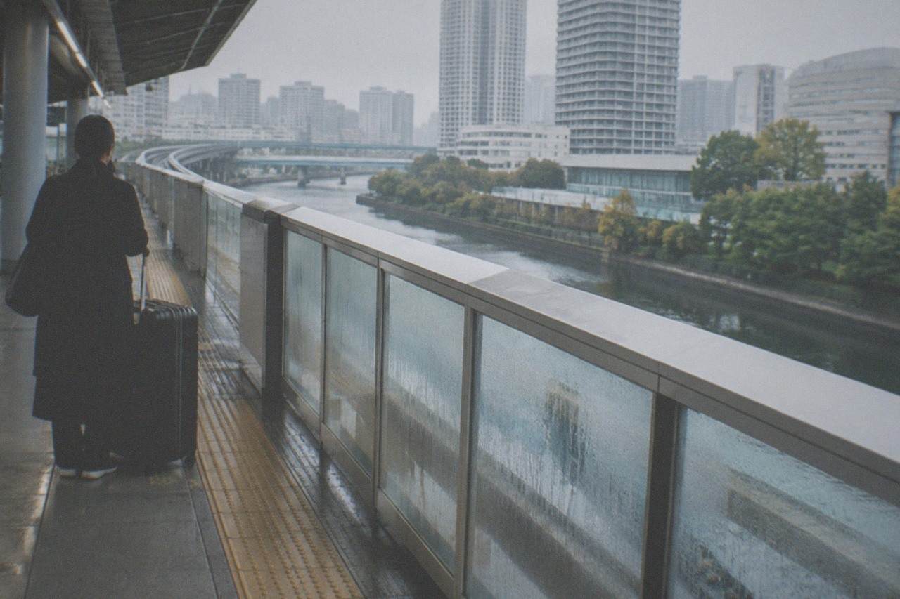 Haneda Airport monorail platform with a traveller waiting beside a large suitcase