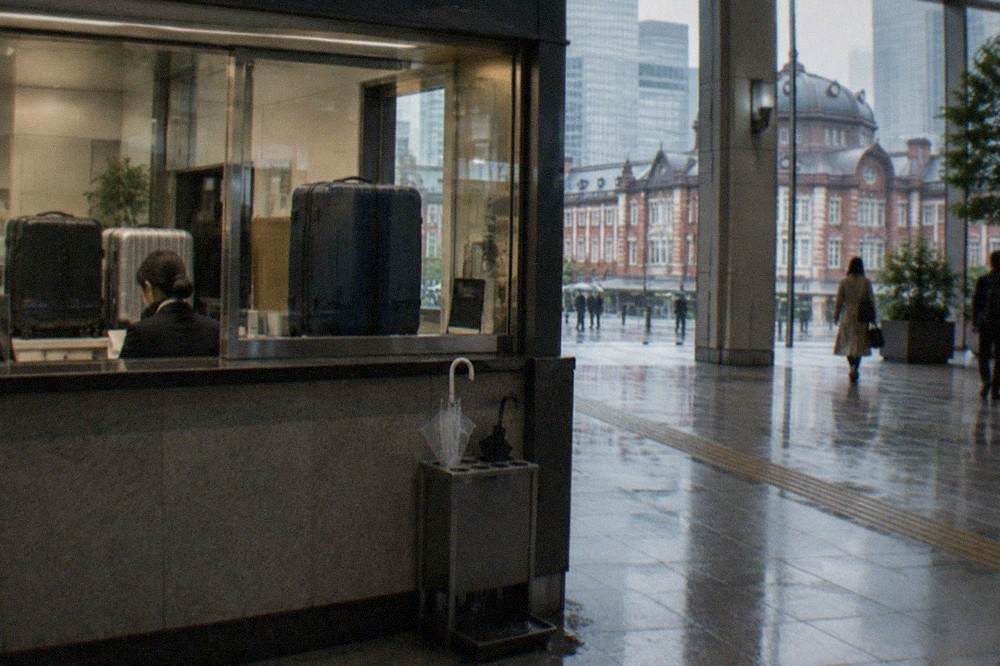 Attended luggage counter window in a Tokyo station concourse with a staffed desk