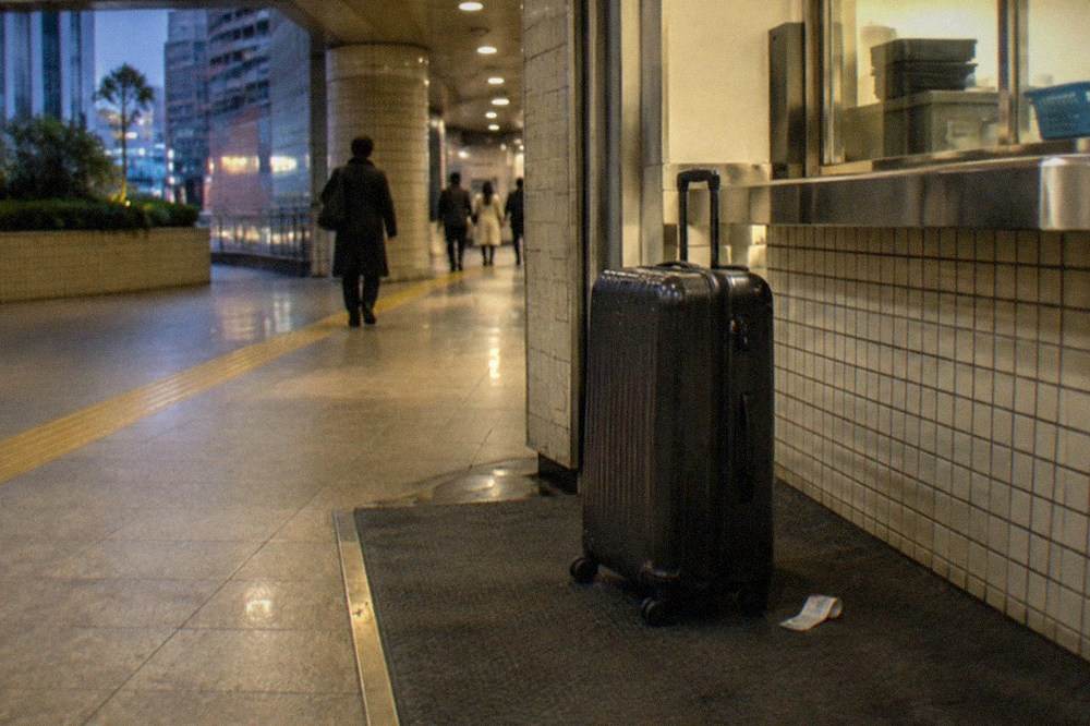 A large suitcase standing beside a station baggage room counter in Tokyo