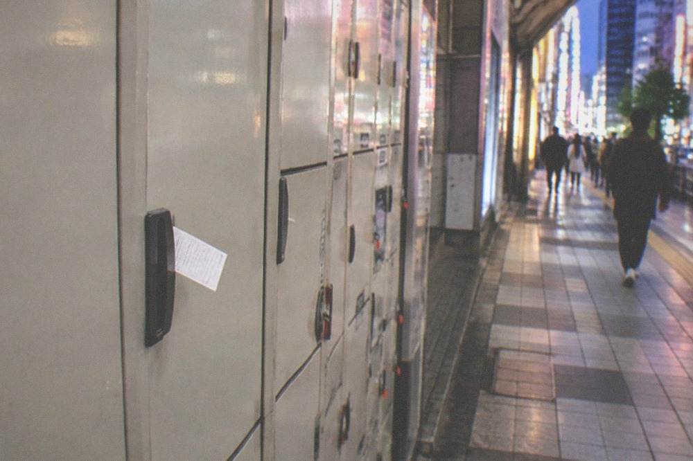 A printed locker receipt resting on a coin locker door in a Tokyo station