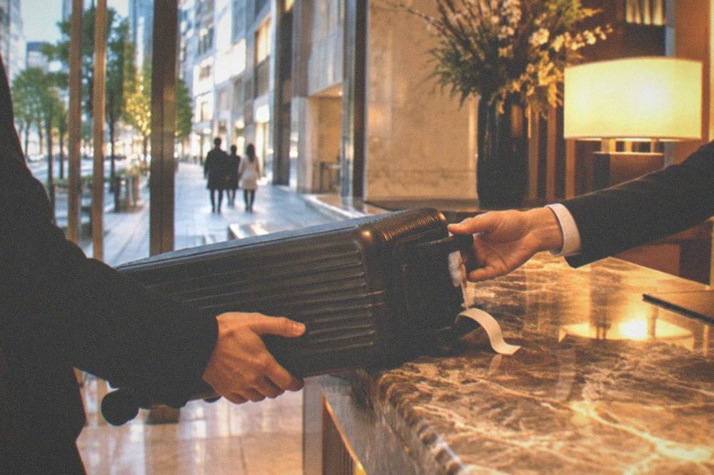 Travel suitcase being handed over at a hotel luggage storage desk