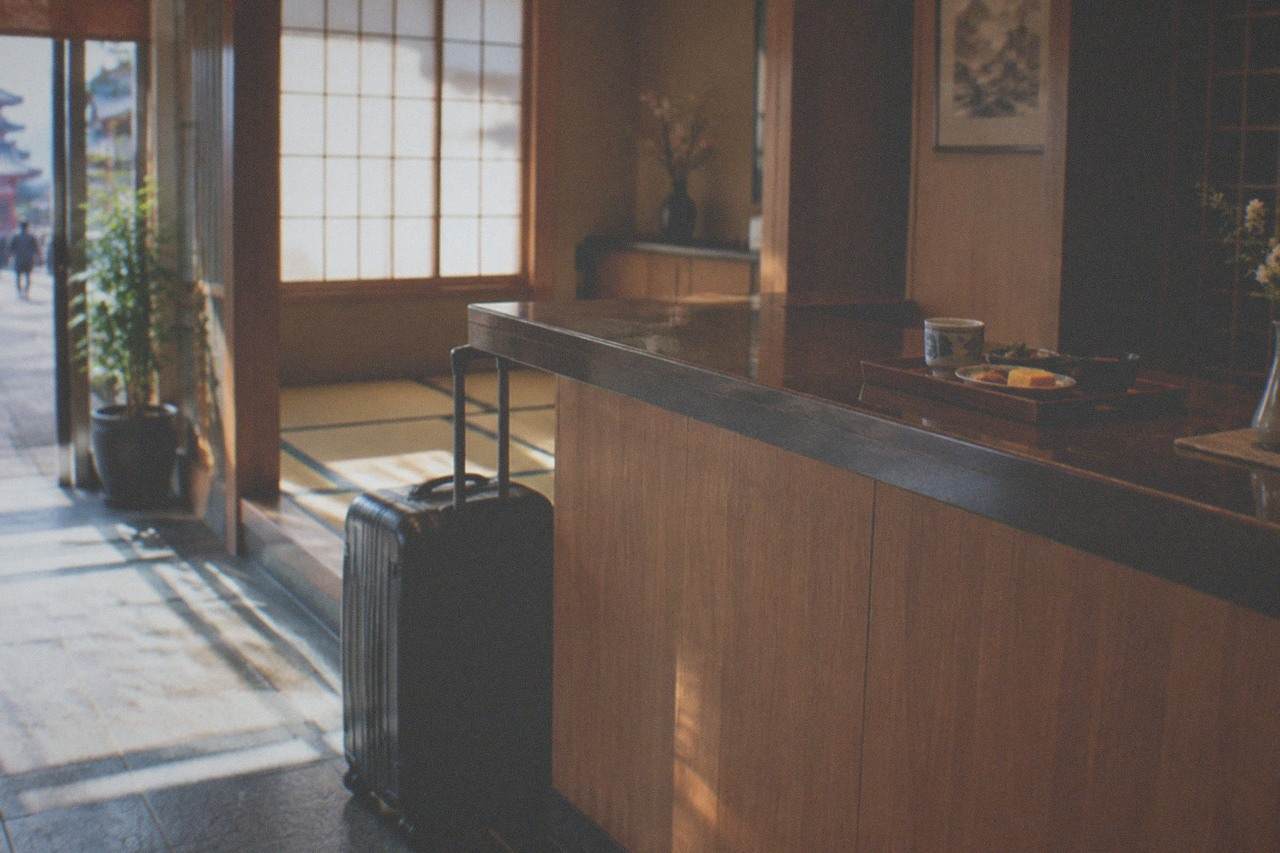 A closed suitcase standing beside the reception desk of a small Tokyo hotel lobby