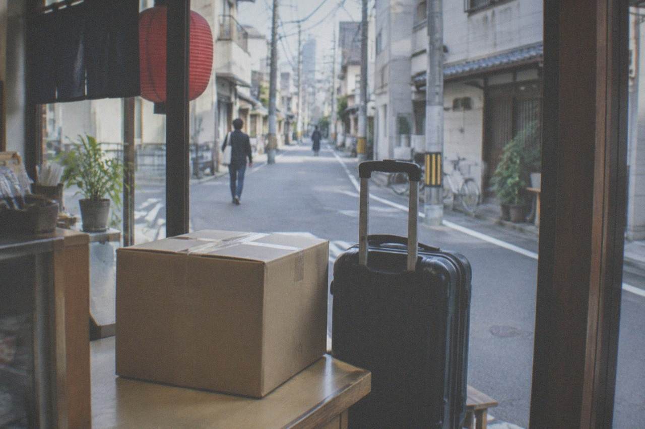 A suitcase with a shipping label standing beside a hotel front desk in Tokyo