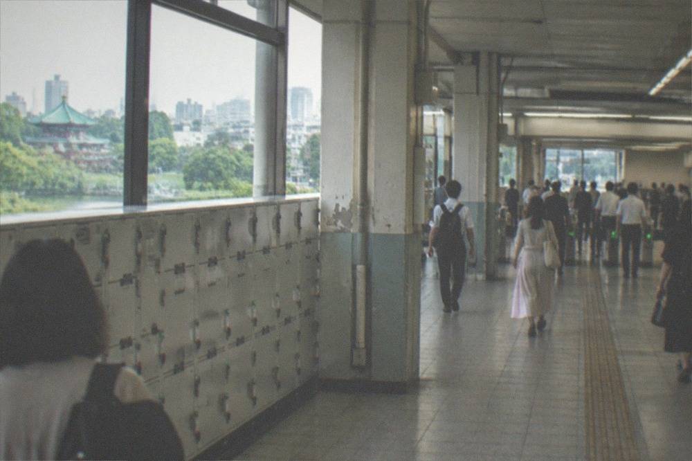 A busy Tokyo station concourse with locker banks along one wall