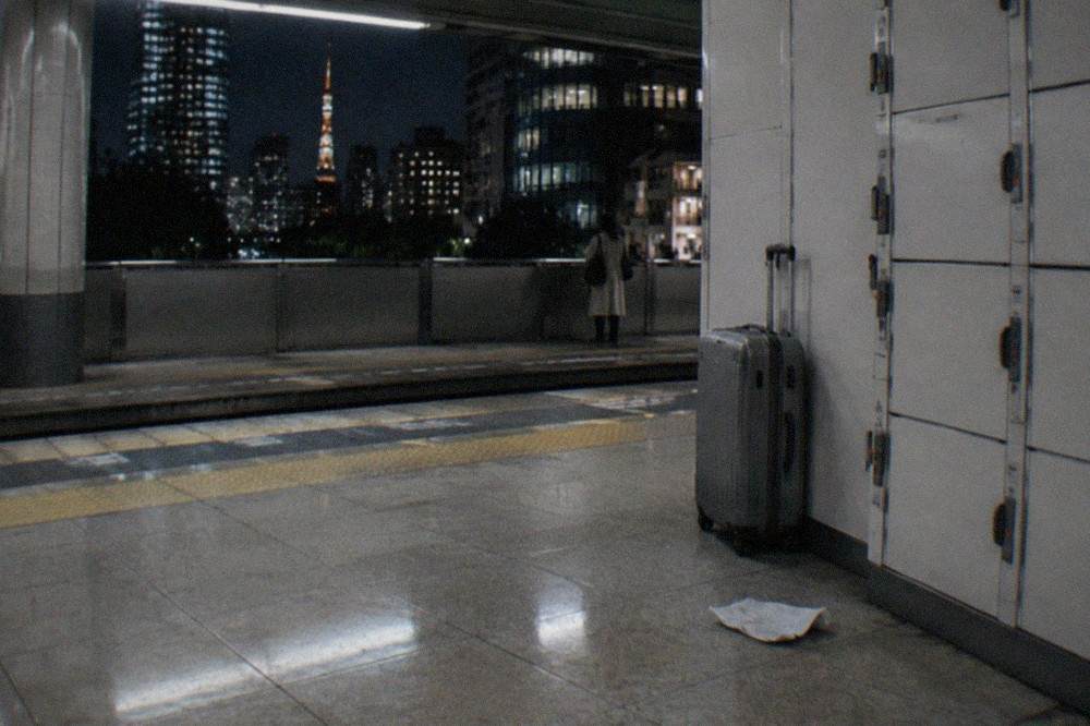 A closed suitcase standing beside a locker bank in a Tokyo subway station