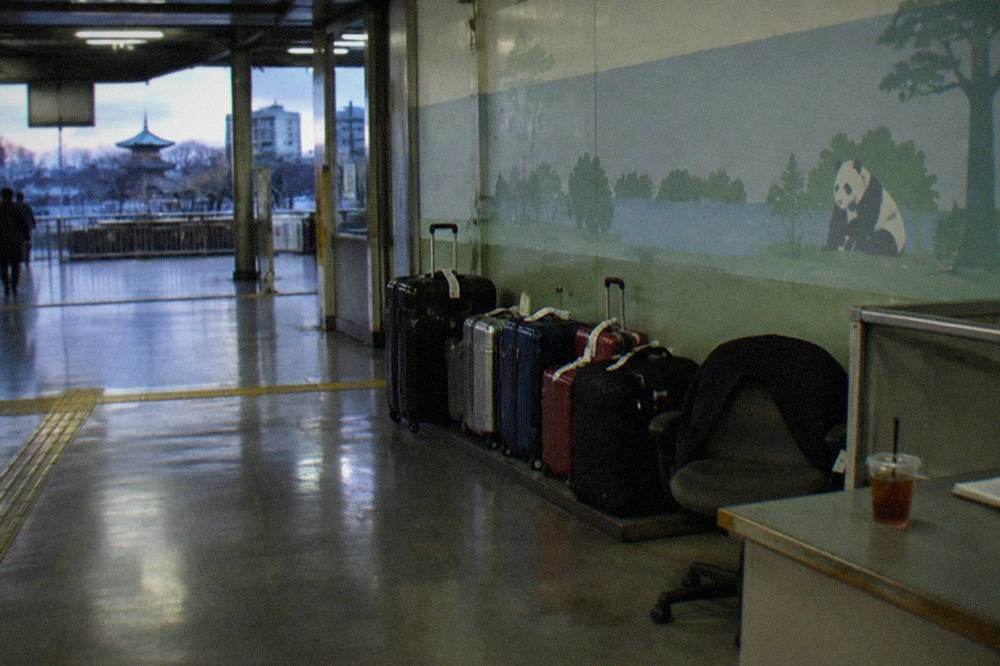 An attended baggage counter with tagged suitcases lined along a wall in a Tokyo station