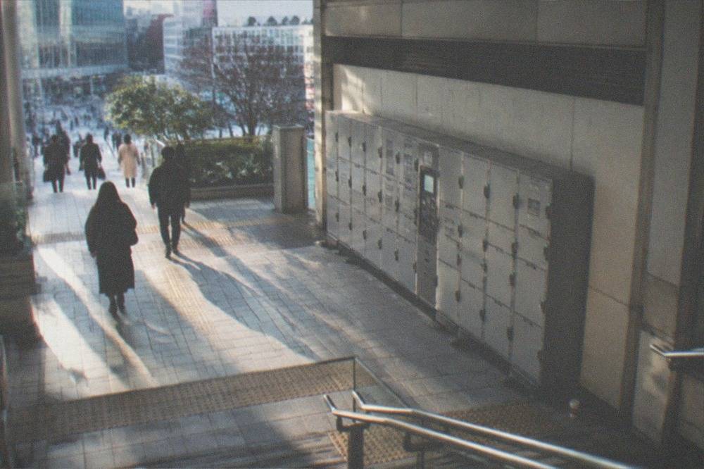 A train station concourse with a row of grey coin lockers along one wall.