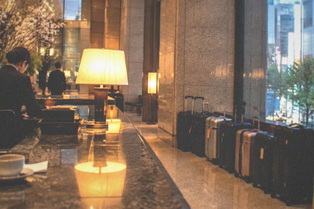 Luggage forwarding counter in a hotel lobby with suitcases lined up for courier collection