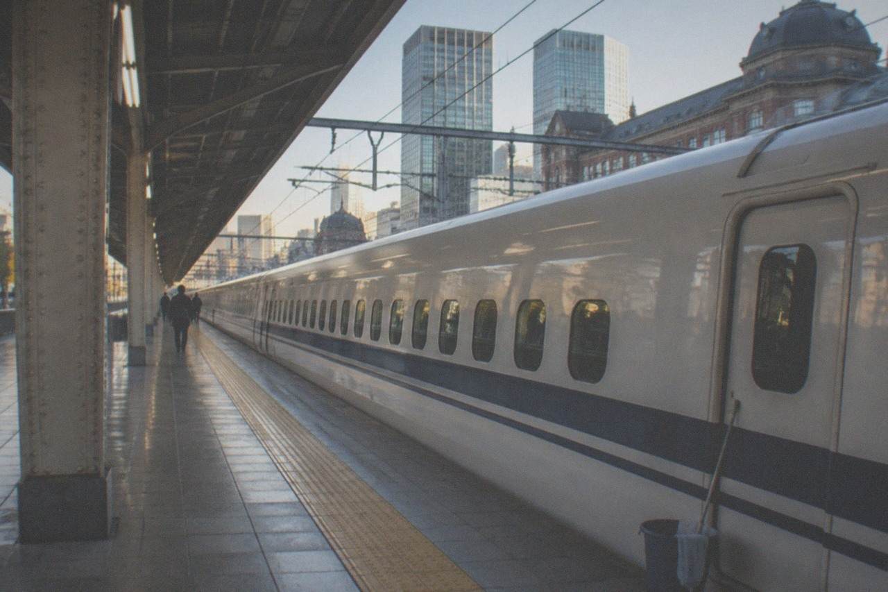 A white Shinkansen train stopped at a station platform beside a yellow safety line