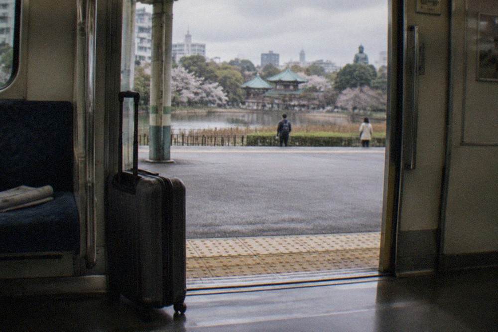 A wheeled suitcase standing beside the doors of a Tokyo Metro train
