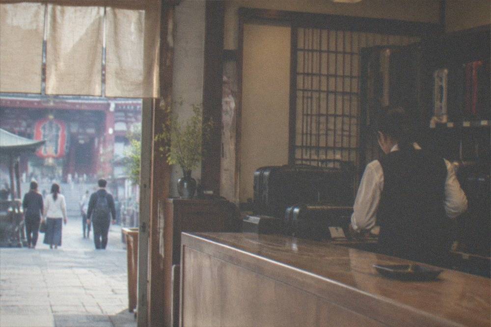 A staffed bag drop counter in a Tokyo shop with suitcases lined behind the desk