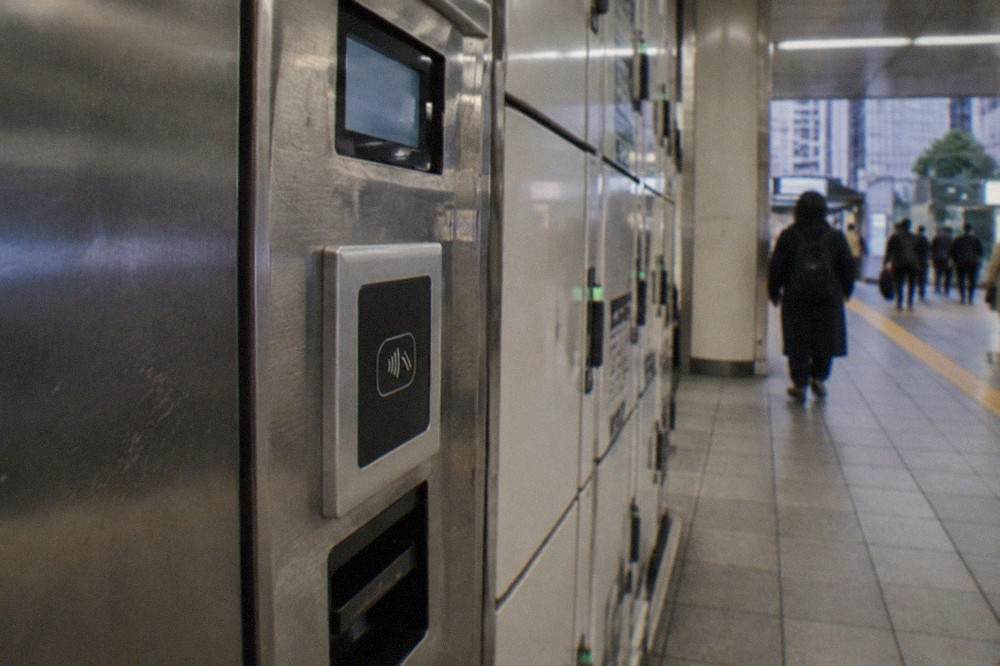 A close view of a coin locker control panel with a card reader slot and a small display screen