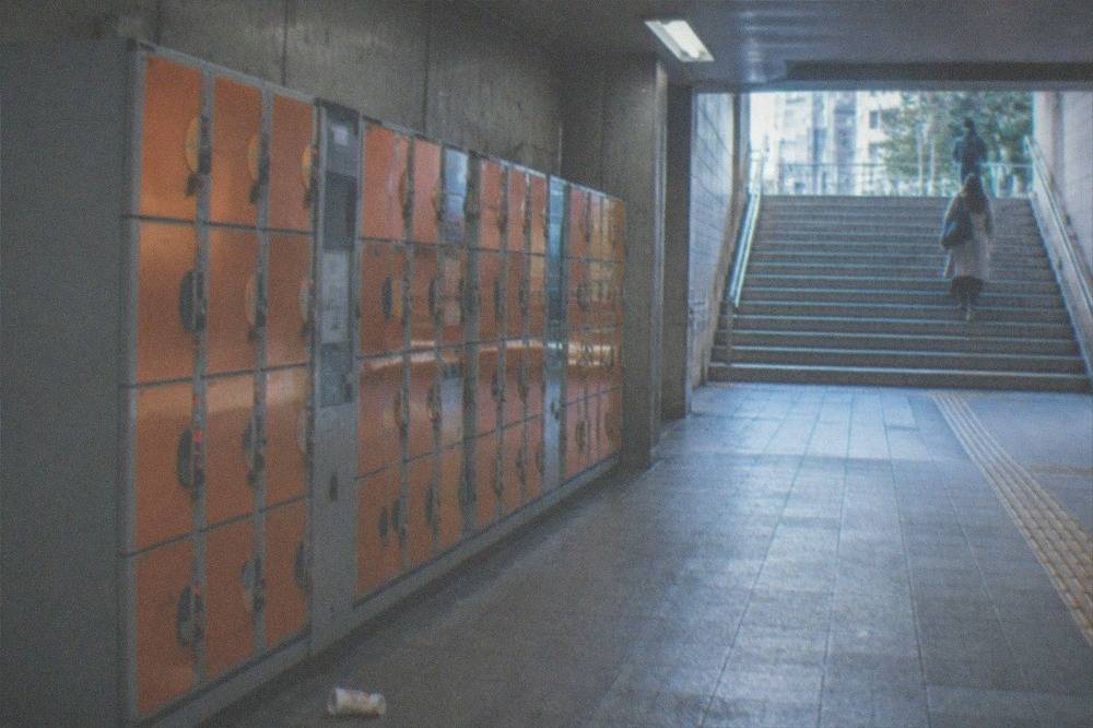 A row of orange and grey coin lockers along a quiet underground passage in a Tokyo station