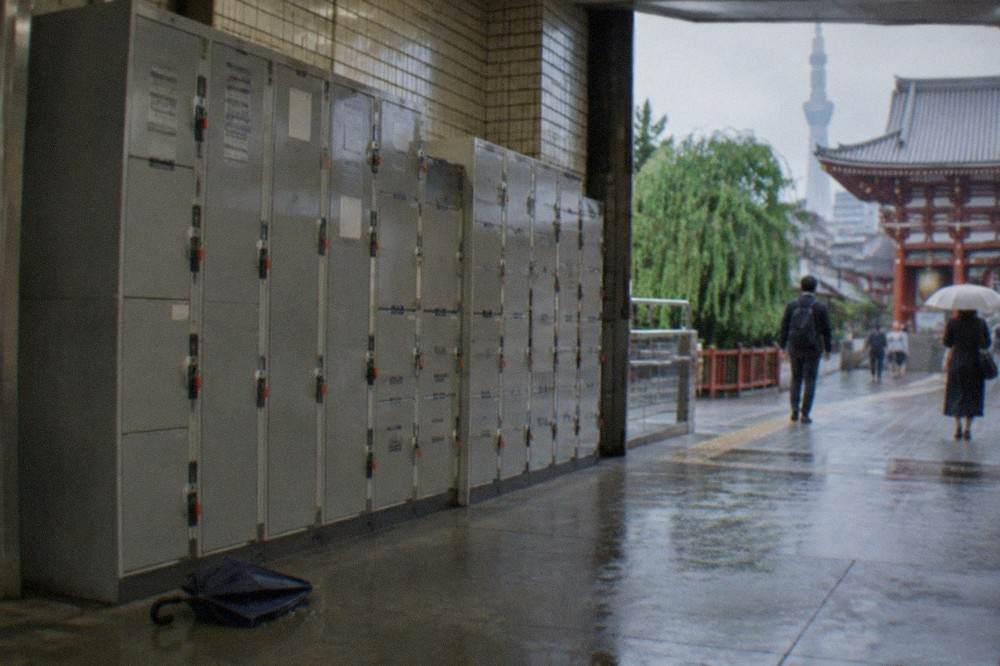 A bank of grey coin lockers of mixed sizes in a Tokyo subway station corridor