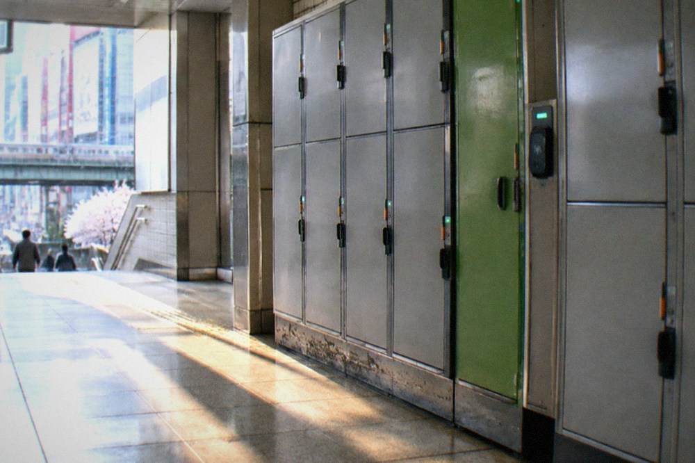 A row of coin lockers at a Tokyo train station with a green door and a Suica reader