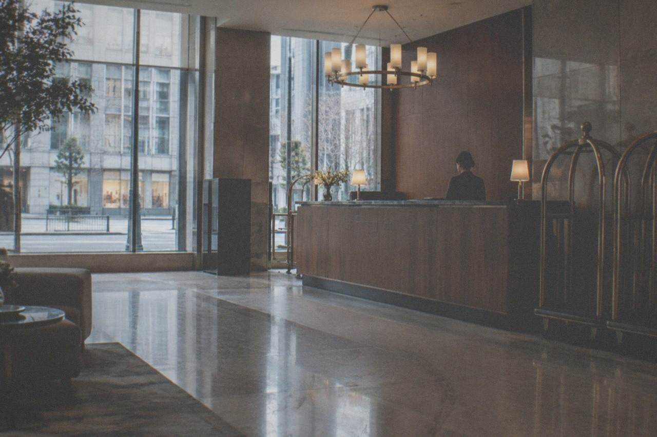 A modern hotel lobby in Tokyo with a wooden reception desk and luggage carts, no people visible