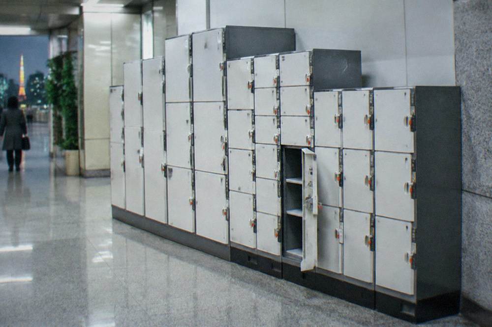 A wall of coin lockers of different sizes inside a Tokyo subway station concourse