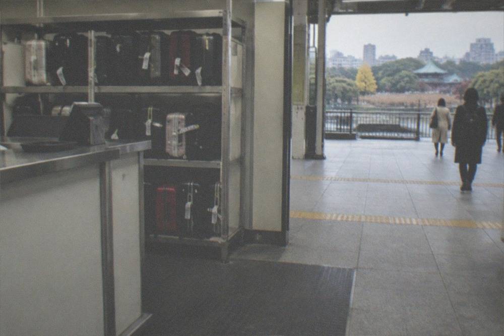 A staffed luggage counter with tagged suitcases behind a counter in a Tokyo station