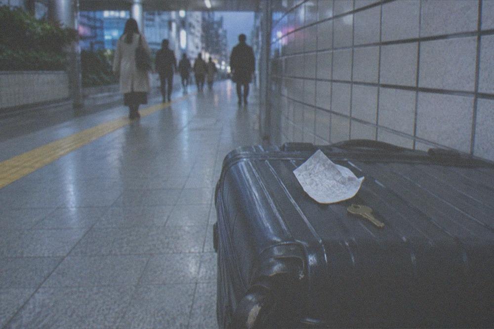 A receipt and a locker key resting on top of a suitcase in a station passage