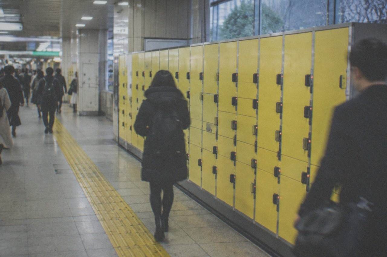 Rows of yellow coin lockers along a busy station corridor in Tokyo