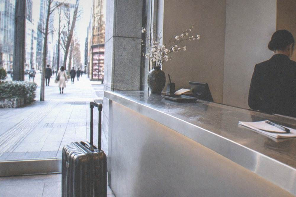 A suitcase standing beside a shop counter with a staffed reception desk