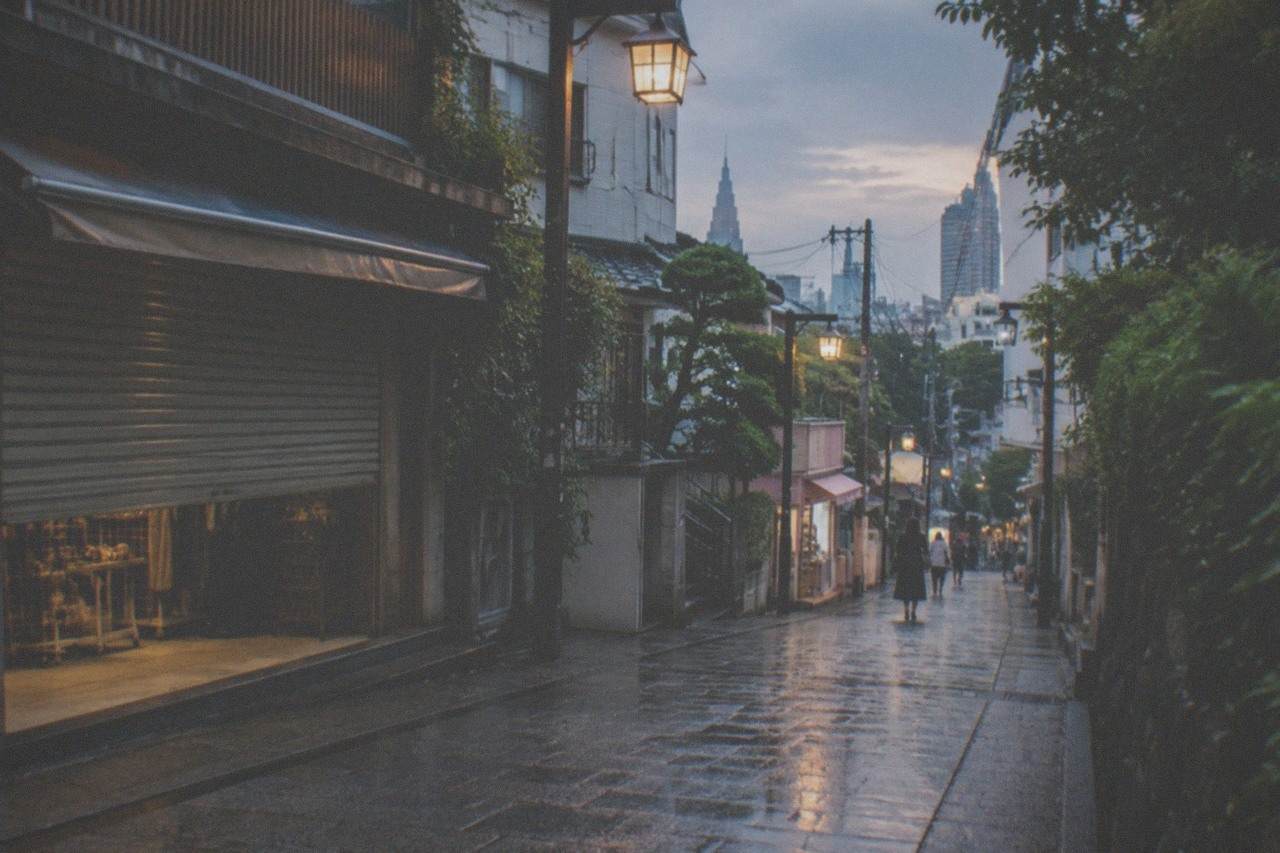 A quiet Tokyo shopping street in the early evening with lanterns and an empty pavement