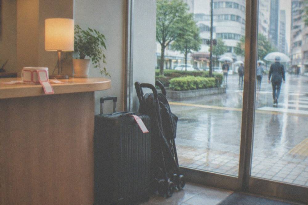 A small shop reception counter with a tagged suitcase and a folded stroller parked beside it