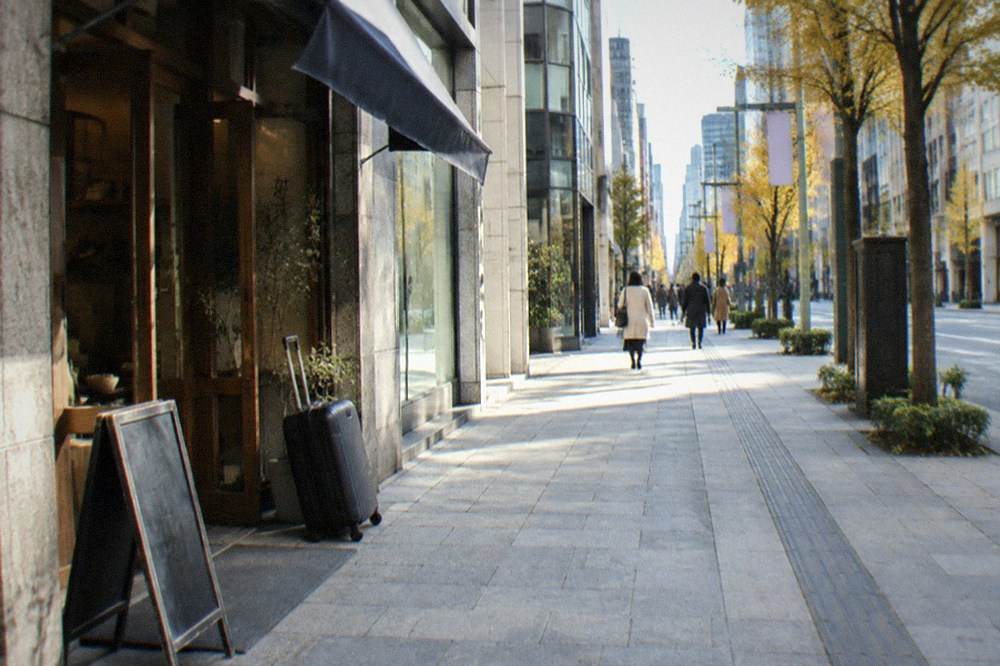 Shopping street with a suitcase leaning at a shop entrance in a Tokyo district, no people.