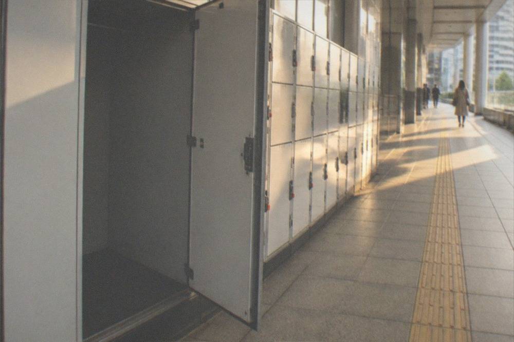 A single large coin locker door standing open and empty beside a row of locked small lockers