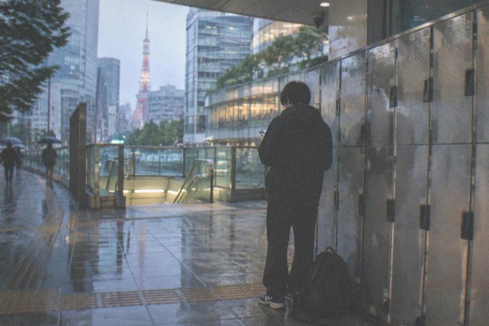 A traveller checking a smartphone while standing beside coin lockers in a Tokyo station